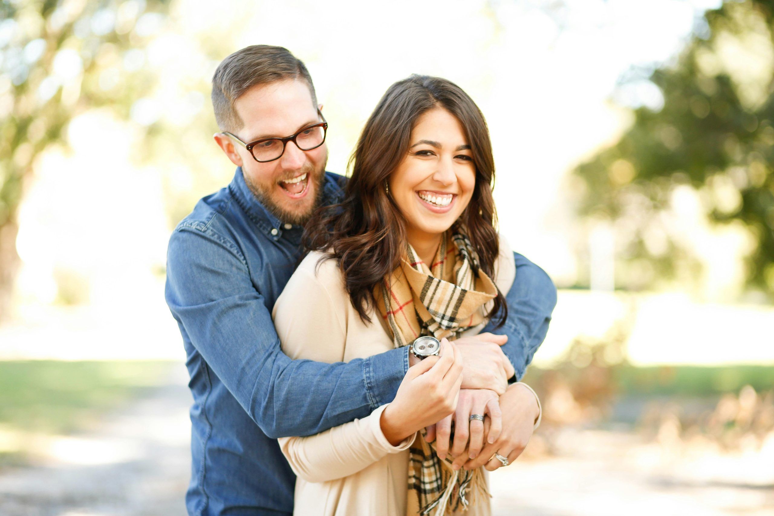 Construyendo la confianza en el amor: pareja sonriente abrazándose al aire libre, reflejando complicidad y felicidad en su relación.