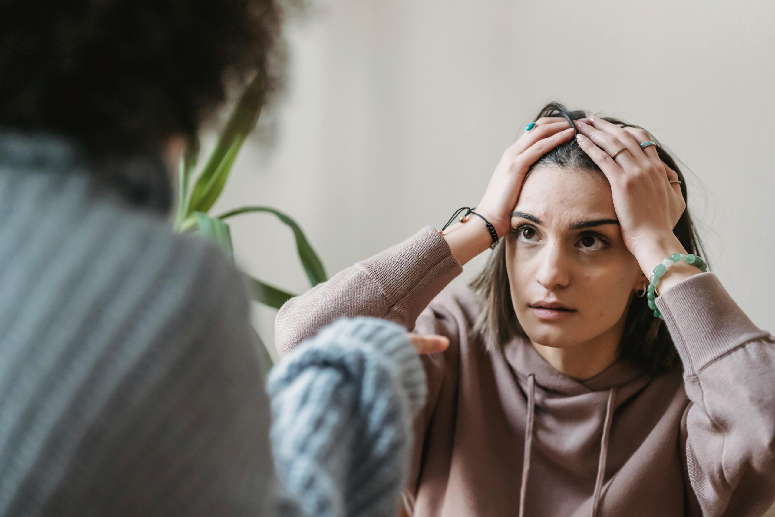 Imagen de dos mujeres, una de espalda y la otra tocandose la cabeza como sintiendo malestar por ser cuestionada