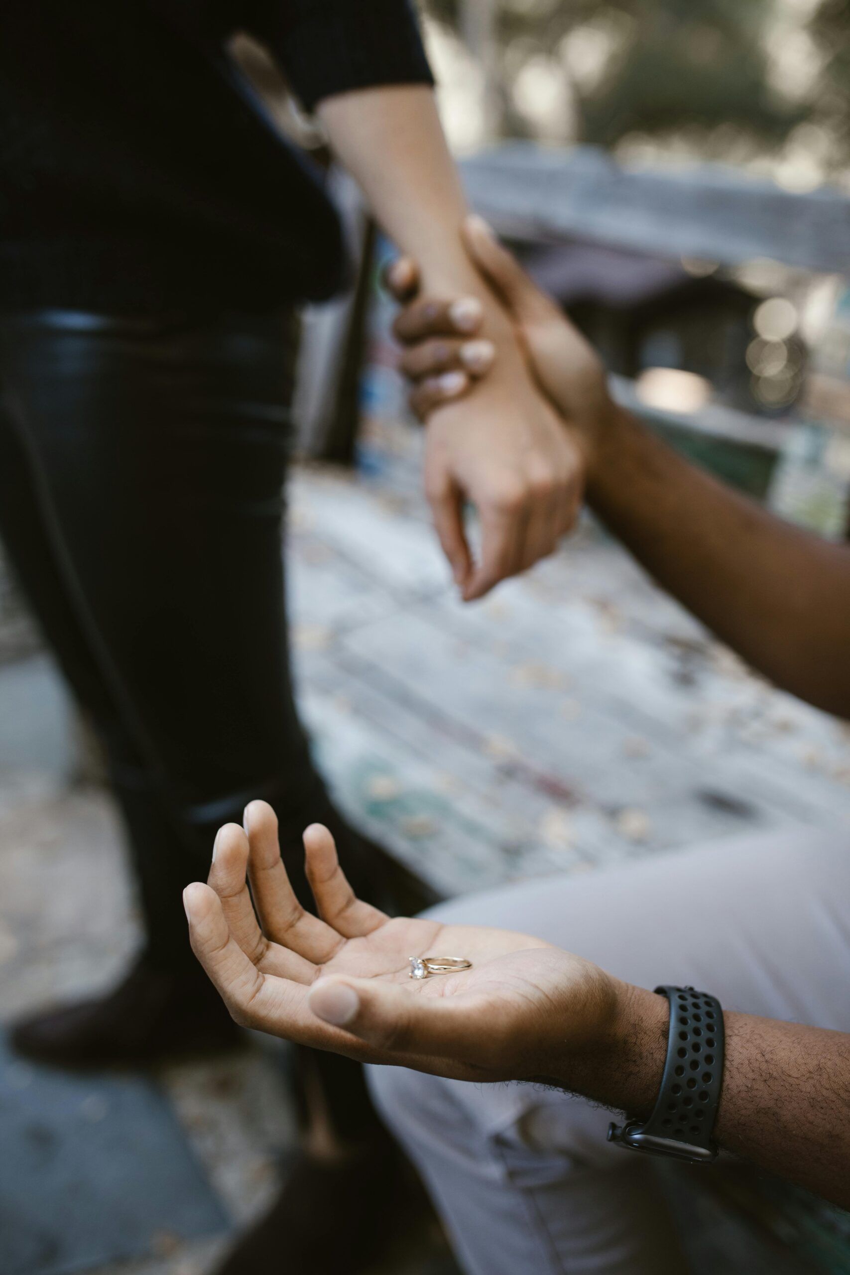 "Imagen de una pareja en una escena emocional: una persona de pie, de espaldas a la otra, mientras entrega un anillo. Una mano intenta sujetar a la otra en un gesto de despedida y conexión, simbolizando la lucha entre dejar ir y retener.